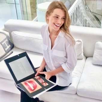 Frau sitzt auf weißem Sofa und hält ein Magazin mit Zahndesigns